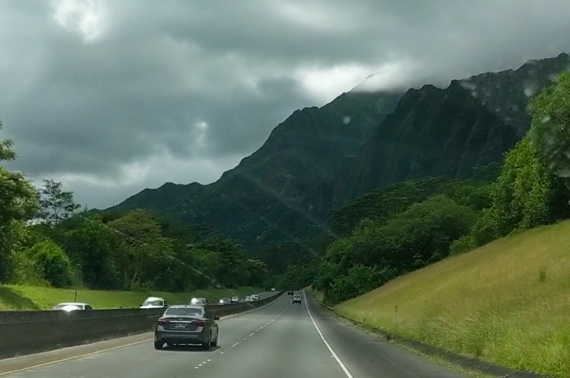 a road in O’ahu Hawai’i surrounded by greenery and mountains